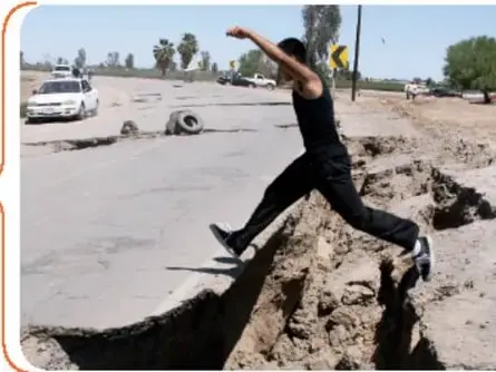 Persona saltando sobre una grieta en el suelo, con un vehículo al fondo, relacionado con el sismo de Baja California de 2010.