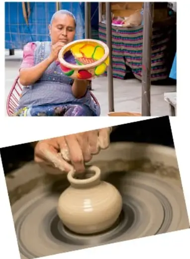 Manos de artesano modelando una vasija de barro en un torno de alfarería.