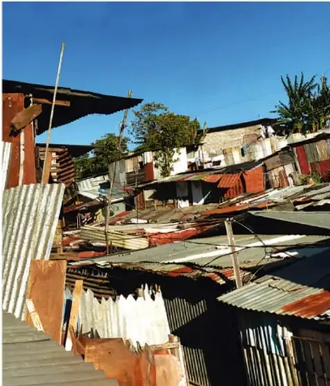 Viviendas precarias construidas con láminas y materiales improvisados en una ladera, que ilustran la pobreza y la marginación.