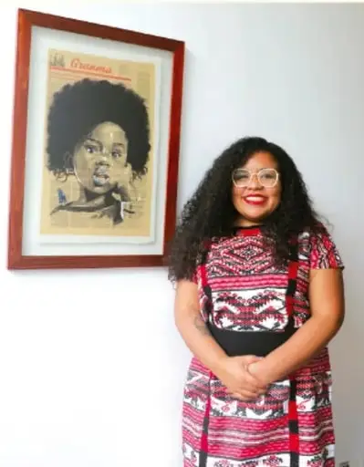 Fotografía de una mujer afro-mexicana sonriente frente a un retrato enmarcado; crédito: Max Jovan Longo Resendiz, Estado de México.