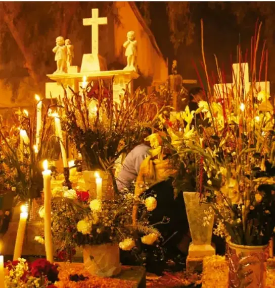 Fotografía de una ceremonia religiosa con velas encendidas, cruces, imágenes de santos y arreglos florales, ilustrando la convivencia del culto eclesiástico con rituales indígenas.