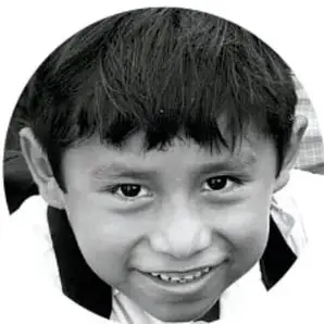 Fotografía en blanco y negro, en forma circular, de un niño sonriente mirando a la cámara.
