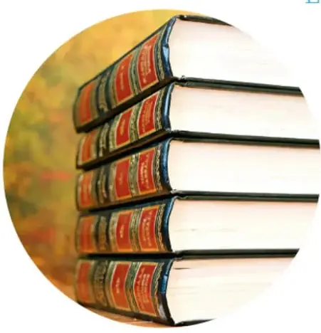 Fotografía circular de una pila de libros antiguos de tapa dura con lomo rojo y dorado, sobre fondo otoñal.