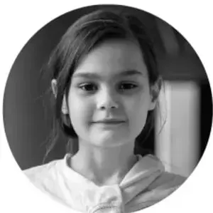 Fotografía en blanco y negro de una niña sonriente con playera clara.