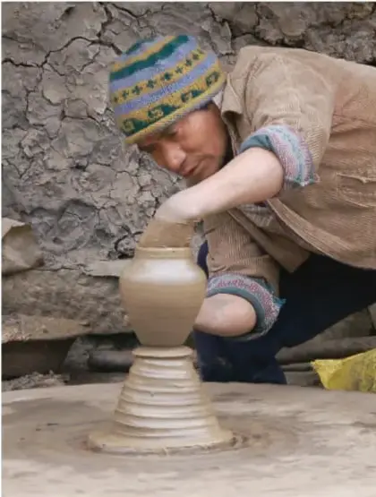 Fotografía de un artesano usando un torno tradicional para dar forma a una vasija de barro (alfarería), ejemplo de tecnología artesanal aplicada a la producción.