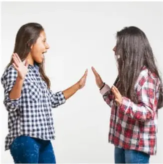 Dos jóvenes conversan manteniendo contacto visual con las manos levantadas.