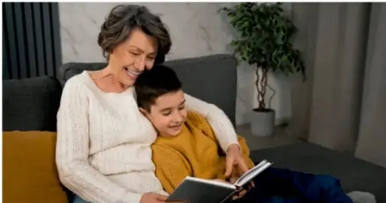 Foto de una adulta y un niño sentados juntos leyendo un libro, ilustrando la lectura compartida.