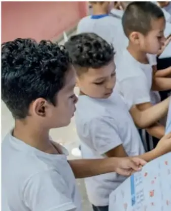 Niños observan y señalan una maqueta o cartel durante una presentación.
