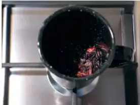Pocillo oscuro sobre fuego, con la infusión de flores de Jamaica en ebullición.
