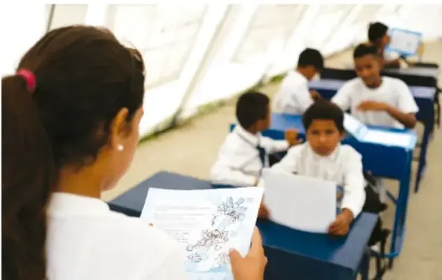 Estudiantes en un aula leyendo y revisando cartas en sus pupitres.