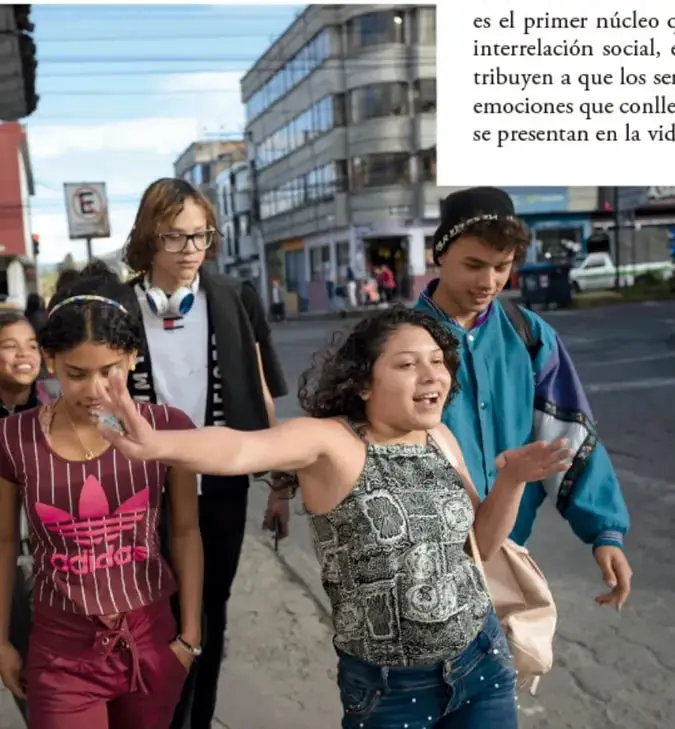 Grupo de adolescentes caminando juntos por una calle urbana, interactuando de manera alegre y espontánea, ilustrando la expresión emocional en la vida cotidiana.