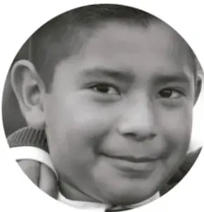 Fotografía en blanco y negro de un niño sonriente con playera clara.