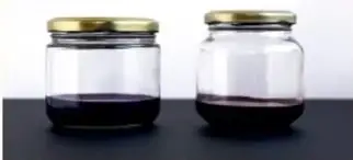 Dos frascos de vidrio con tapa dorada que contienen líquido oscuro, probablemente extracto de hibisco y de col morada.