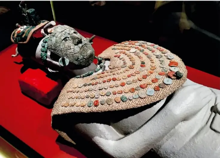 Escultura maya en piedra de una cabeza con elaborado tocado, probablemente representación de Pakal o de un gobernante maya.