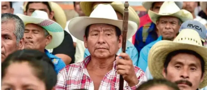 Fotografía de un grupo de hombres indígenas, varios con sombrero de paja, uno de ellos con un bastón o vara ceremonial; imagen que ilustra la organización comunitaria y las luchas de los pueblos originarios.