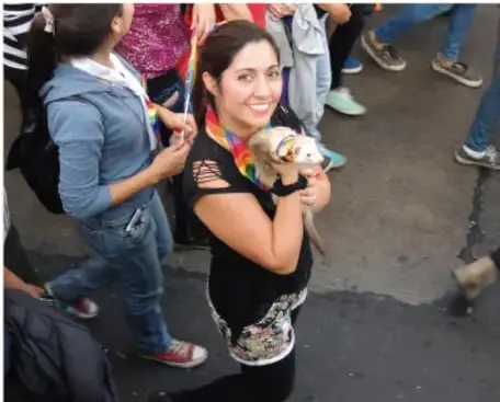 Adolescentes participando en una marcha pacífica, una de ellas sostiene un cartel con la bandera del orgullo.