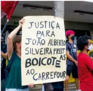 Manifestantes sostienen un cartel pintado a mano que dice "Justiça para João Alberto Silveira Freitas. Boicote ao Carrefour".