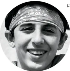 Fotografía circular en blanco y negro de un niño sonriente con un paliacate en la cabeza.