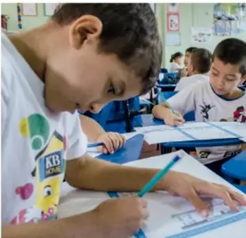 Niño escribiendo en un cuaderno en el salón de clases.
