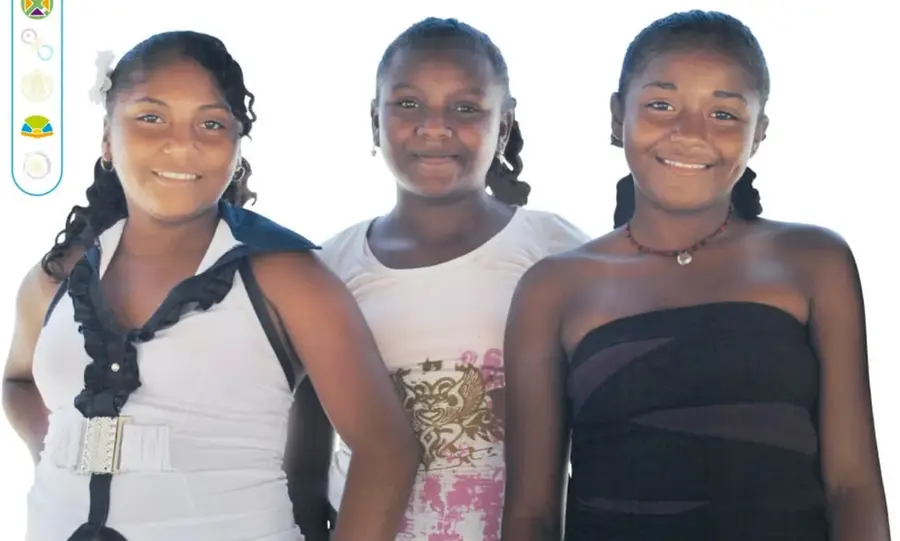 Fotografía de tres niñas y jóvenes morenas, sonrientes, con trenzas, sobre fondo claro.