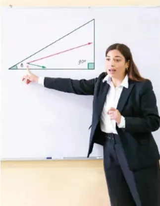 Fotografía de una maestra frente a un pizarrón donde se observa un triángulo rectángulo con ángulos marcados (θ y 90°), señalando con un puntero mientras explica trigonometría.