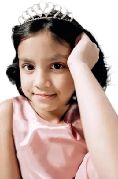 Fotografía de una niña con corona y vestido rosa, con la mano en la cabeza, que ilustra a María.