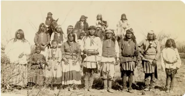 Fotografía antigua titulada 'Un campamento apache durante el Porfiriato', con personas indígenas frente a chozas.