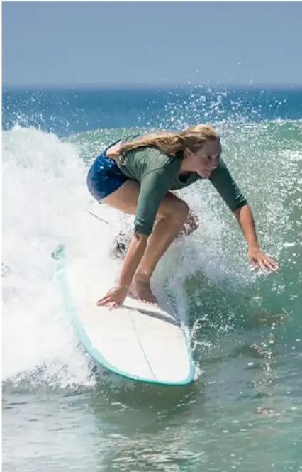 Fotografía de un surfista varón realizando una maniobra sobre una ola con mucha espuma blanca.