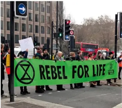 Manifestantes con una pancarta verde que dice REBEL FOR LIFE, símbolo de Extinction Rebellion.