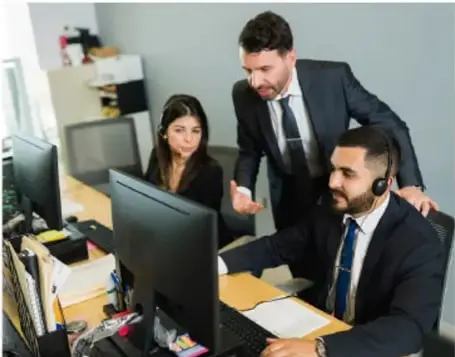 Fotografía de un equipo de profesionales (tres personas con traje) trabajando frente a computadoras en una oficina, ilustrando un servicio empresarial.