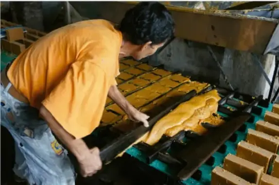 Trabajador manipulando bloques de material en moldes, ilustrando procesos de producción