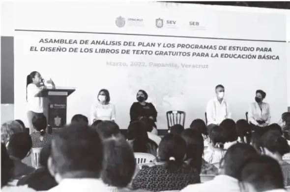 Fotografía en blanco y negro de la 'Asamblea de análisis del Plan y los programas de estudio para el diseño de los libros de texto gratuitos para la educación básica', marzo 2022, Papantla, Veracruz, con logos SEV y SEB, mesa directiva y asistentes.