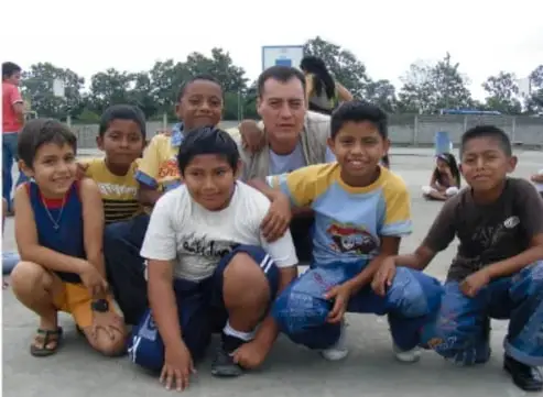 Fotografía de un grupo de niños y un adulto sentados en el patio, conviviendo.