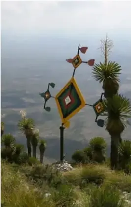 Paisaje de montaña con estructura decorativa textil colorida (tzicuri) sobre campo abierto.