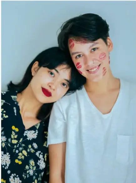 Fotografía de una joven y un joven sonriendo, con marcas rojas en el rostro, abrazados; ilustra la diversidad y la salud sexual.