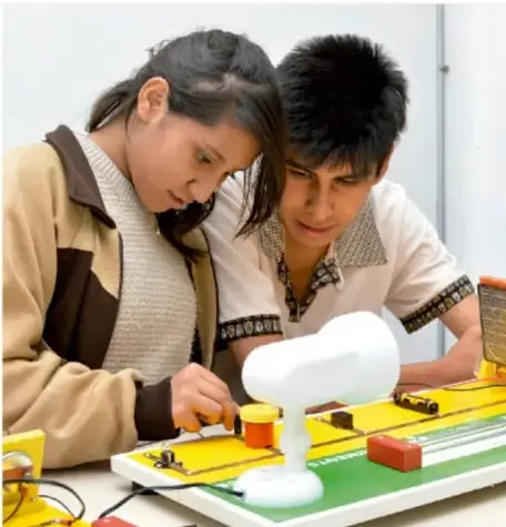 Dos estudiantes trabajando con un aparato o modelo científico sobre una mesa, ilustrando la práctica científica escolar.