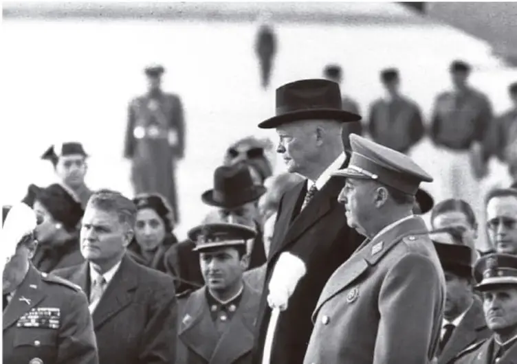 Fotografía en blanco y negro de Francisco Franco junto a militares y civiles, probablemente en un acto oficial o desfile.