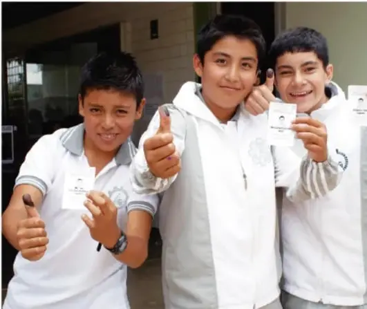 Tres jóvenes sonrientes sostienen credenciales de identificación, simbolizando la ciudadanía y el derecho al voto.