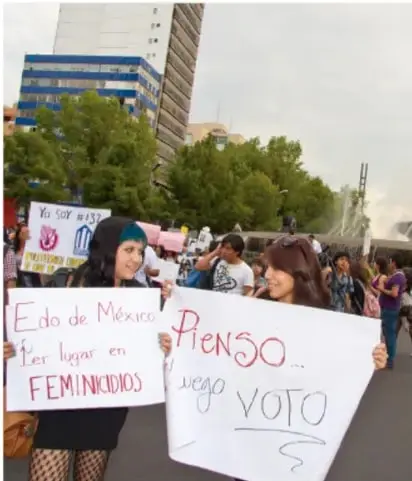Fotografía de una marcha feminista en México. Varias personas sostienen carteles. Uno dice 'Edo de México 1er lugar en FEMINICIDIOS' y otro 'PIENSO... luego VOTO'.