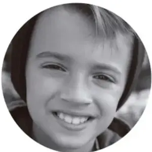 Fotografía en blanco y negro de un niño sonriente, como ejemplo de estudiante que explora un libro.