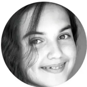 Fotografía en blanco y negro de una niña sonriente, con cabello largo oscuro.