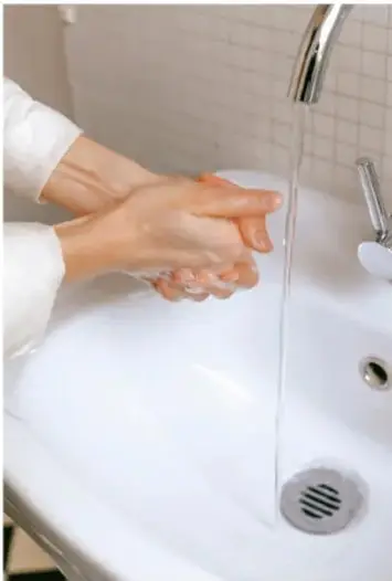 Fotografía de manos lavándose con agua y jabón en un lavabo.