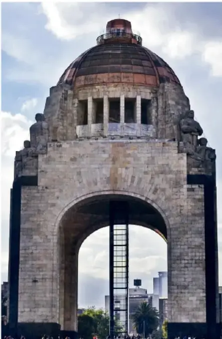 Fotografía del Monumento a la Revolución en la Ciudad de México: gran arco de piedra con cúpula metálica y columnas, bajo un cielo con nubes.