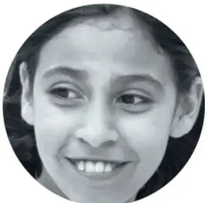 Fotografía en blanco y negro del rostro sonriente de una niña, con encuadre circular.