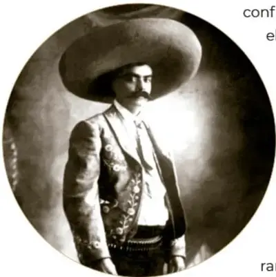 Fotografía circular en sepia de Emiliano Zapata con sombrero ancho, uniforme militar y banda cruzada, de pie. Pie de foto: 'Emiliano Zapata, ca. 1914. © (5934). Secretaría de Cultura. INAH.SINAFO.FN.MX.'