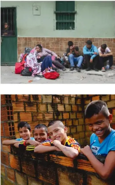 Grupo de personas migrantes sentadas en el suelo junto a maletas y bolsas, frente a una pared verde con ventana enrejada.