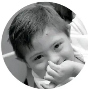 Fotografía en blanco y negro de un niño riendo con la mano en la boca.
