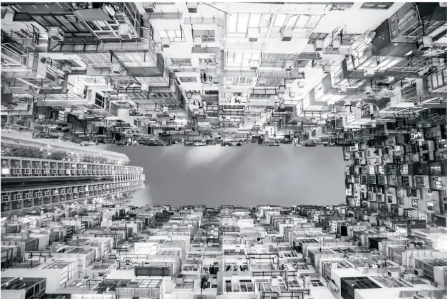 Fotografía en blanco y negro de una ciudad vista desde arriba, con edificios que convergen hacia el centro y generan sensación de profundidad.