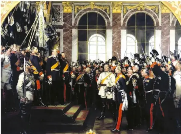 Pintura histórica que muestra una gran asamblea de hombres uniformados y condecorados en un salón palaciego con arcos y ventanales. Representa probablemente la proclamación del Imperio alemán o una ceremonia oficial del proceso de unificación.
