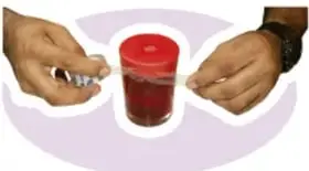 Manos colocando el globo rojo como tapa del frasco.